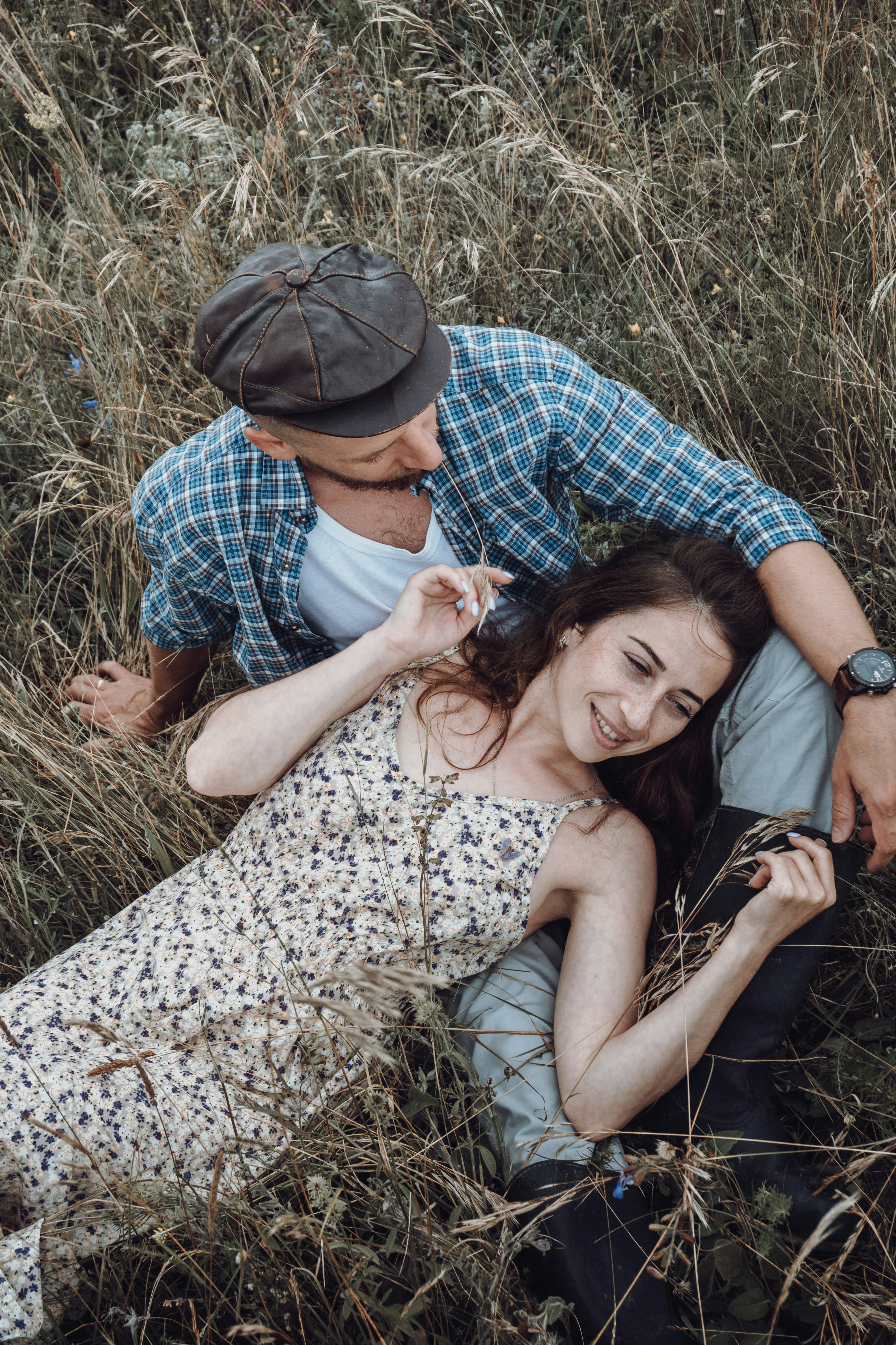 man and woman kissing on brown grass during daytime